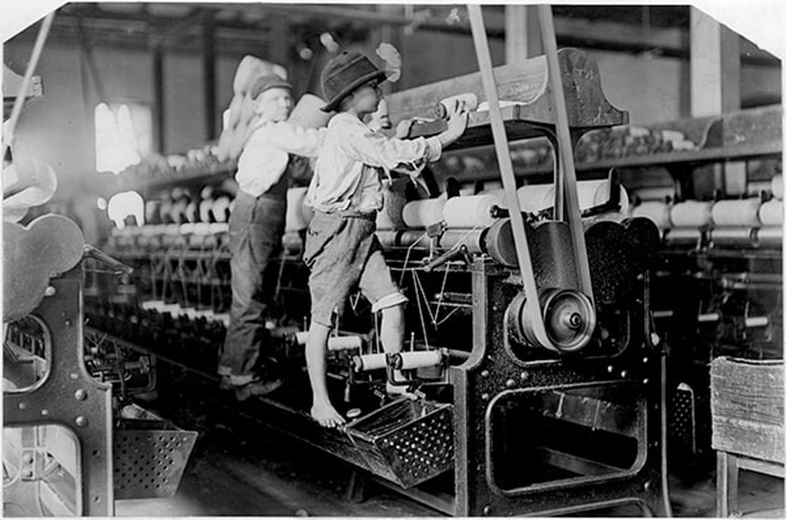 Two boys working on a machine in a Georgia factory, 1909. Children would have to climb the large machines to reach the controls. Their small hands and feet would frequently get caught in the machinery and they would be maimed for life.