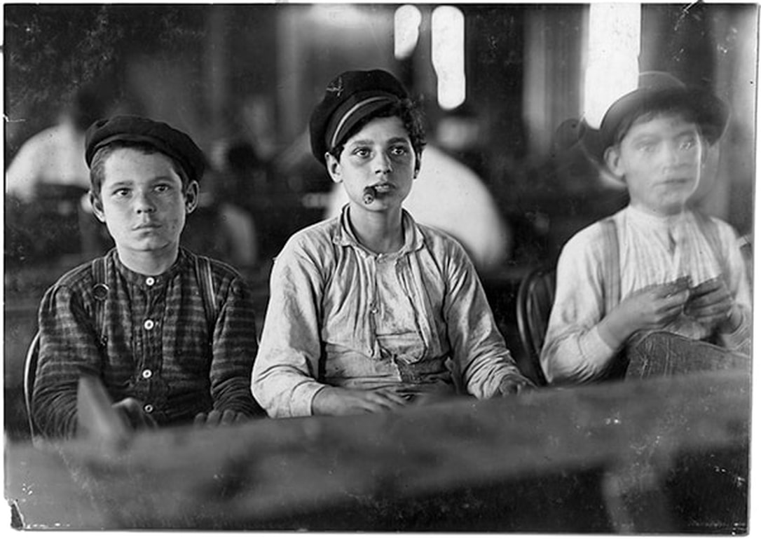 The photograph showed three young boys sitting side by side, busy at work. The boy in the middle is smoking a cigar. You are immediately drawn to their glassy eyes staring off into the distance, with expressions frozen in time.
